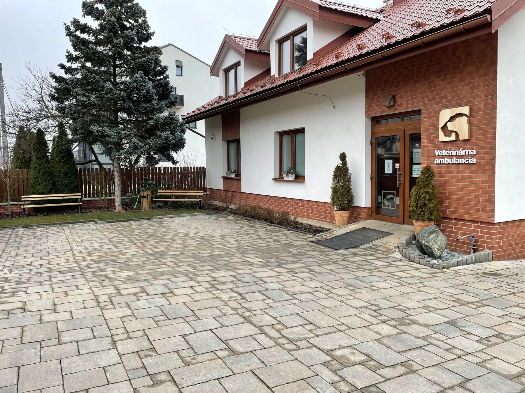 Budova veterinárnej ambulancie na Osloboditeľov 27: biely dom s tehlovou fasádou, vchod s tabuľou Veterinárna ambulancia a dláždený dvor